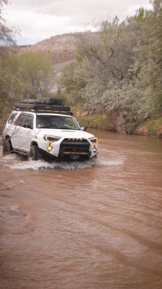 a white truck driving through a muddy river