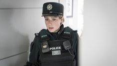 a woman police officer standing in front of a wall with her hand on her hip