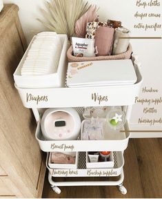 a white cart with lots of items in it on top of a wooden floor next to a wall