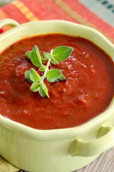 a green bowl filled with red sauce on top of a table