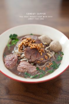 a white bowl filled with meat and veggies on top of a wooden table