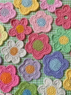 crocheted flowers are laid out on a green and white checkered tablecloth