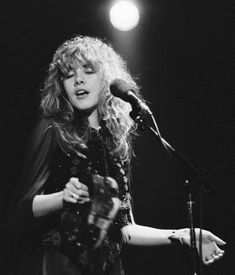 a black and white photo of a woman on stage with a microphone in her hand