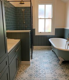 a bath tub sitting next to a window in a bathroom with blue tiles on the floor