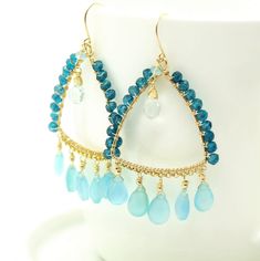 "Blue Chalcedony, Aquamarine and Blue Topaz Hoop Earrings, Chandelier Earrings in Gold Filled Sky Blue Chalcedony Briolette beads are wrapped with high quality 14k gold filled wire and swing from a gold filled hoops. The Hoops are wire wrapped with Blue Mystic Topaz beads. Aquamarine Briolette drops dangle in the middle of the frames. These are natural, excellent AAA quality gems, beautifuly faceted and shimmering. These are the earrings that make you feel happy just by looking at them - magical Blue Teardrop Gemstone Hoop Earrings, Blue Gemstone Chandelier Drop Earrings, Light Blue Necklace, Pink Gemstone Necklace, Blue Chandelier, Blue Sapphire Jewelry, Indian Jewelry Earrings, Blue Sapphire Necklace, Unique Handcrafted Jewelry