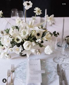 the table is set with white flowers and silverware