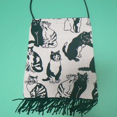 a black and white bag with cats on it sitting on a green surface, next to a pair of scissors