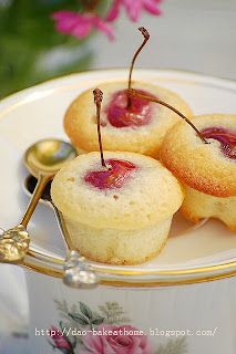 three small pastries on a plate with spoons and flowers in the back ground