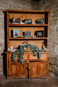 an old wooden cabinet with pictures on it and a plant growing out of the top