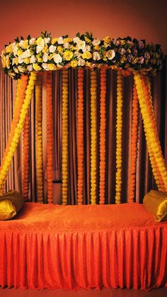 an orange and yellow decorated stage with flowers on the headboard, along with pillows