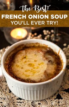 french onion soup in a white bowl with candles behind it