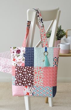 a multicolored patchwork bag sitting on top of a white chair next to a potted plant