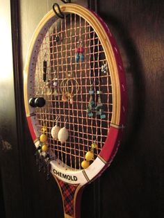 a tennis racket hanging from the side of a door with earring hooks on it