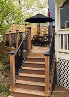 a wooden deck with black railing and an umbrella on the patio area next to it