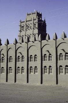 a large building made out of sand with arched windows and arches on the sides, in front of a blue sky