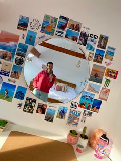 a man standing in front of a mirror with many pictures on the wall behind him