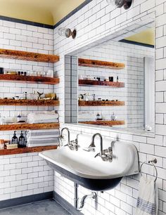 a bathroom with white tiles and wooden shelves