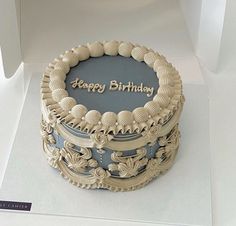 a birthday cake with the words happy birthday written on it in gold and blue frosting