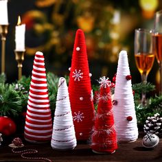 small christmas trees are lined up on a table next to wine glasses and candlesticks