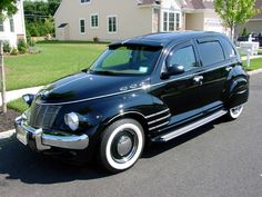 an old black car parked on the side of the road in front of a house