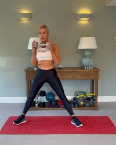 a woman is standing on a yoga mat and taking a selfie with her cell phone