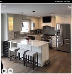 a kitchen with an island and three stools next to the counter top in front of it