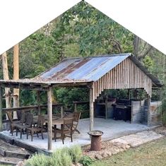 an outdoor kitchen and grill area in the middle of a wooded area with picnic tables