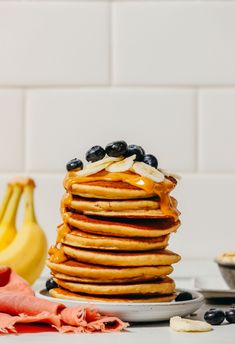 a stack of pancakes with blueberries and bananas