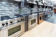 a large kitchen with stainless steel appliances and wood flooring on the walls, along with tiled backsplash