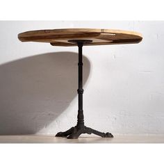 a wooden table sitting on top of a white wall next to a black metal stand