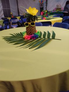 a table topped with a pineapple surrounded by palm leaves and sunglasses on top of it