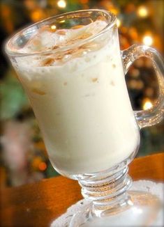 a glass filled with liquid sitting on top of a table next to a christmas tree