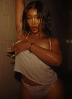 a woman in a white bathing suit standing next to a bath tub with her arms up