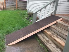 a wooden ramp sitting in the grass next to a house