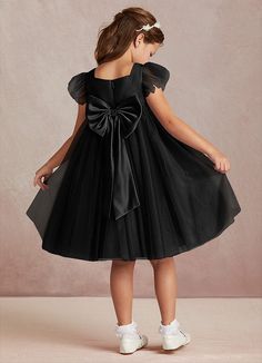 Kalio is our adorable tulle and matte satin flower girl dress. She features a square neckline that is framed with charming short flutter sleeves. She has an empire waist that offers comfort and ease of movement. The flowy A-line skirt adds whimsy while the removable bow gives this dress versatility. This dress is not only perfect for a flower girl at a wedding but also versatile enough for other special occasions. Black And White Flower Girl Dress, Dresses In Black, Black Flower Girl Dress, Satin Flower Girl Dress, Girls Black Dress, Infant Flower Girl Dress, White Flower Girl Dresses, Flower Girl Dresses Tulle, Satin Flowers