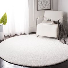 a white chair sitting on top of a rug in a living room next to a window