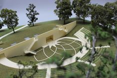 an architectural model of a building on a hill with trees in the foreground and a circular staircase leading up to it