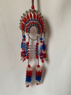 a red, white and blue beaded wind chime hanging from a hook on a wall