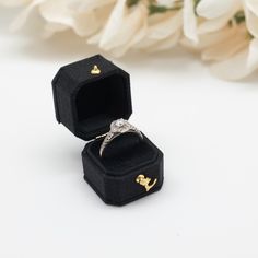 an open ring box sitting on top of a table next to white flowers and a bouquet