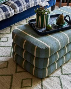 a green and white striped ottoman sitting on top of a rug next to a blue couch