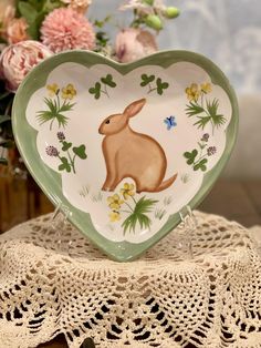 a heart shaped plate with an image of a rabbit on it and flowers in the background