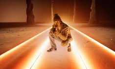 a man standing in the middle of a walkway with his hands on his face and lights behind him