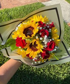 a bouquet of sunflowers and roses is being held by someone's hand