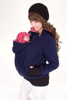 a woman holding a baby wearing a blue sweater and black hat with stars on it