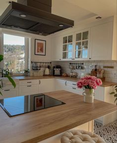 a kitchen with white cabinets and wood counter tops, an oven hood over the stove