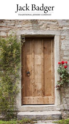 an old wooden door in front of a stone building with flowers growing on the side