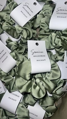 many tags are attached to the back of some green satin ribbons with names on them