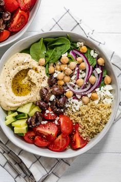 two bowls filled with different types of food on top of a white table cloth next to each other