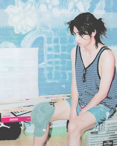 a woman sitting on top of a wooden floor in front of a blue and white wall