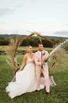 a bride and groom standing in front of a wedding arch with water shooting out from it